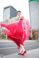 A woman in a red dress is dancing in the middle of the street.