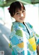 A woman in a blue and green kimono smiles at the camera.