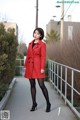 A woman in a red coat is posing for a picture.